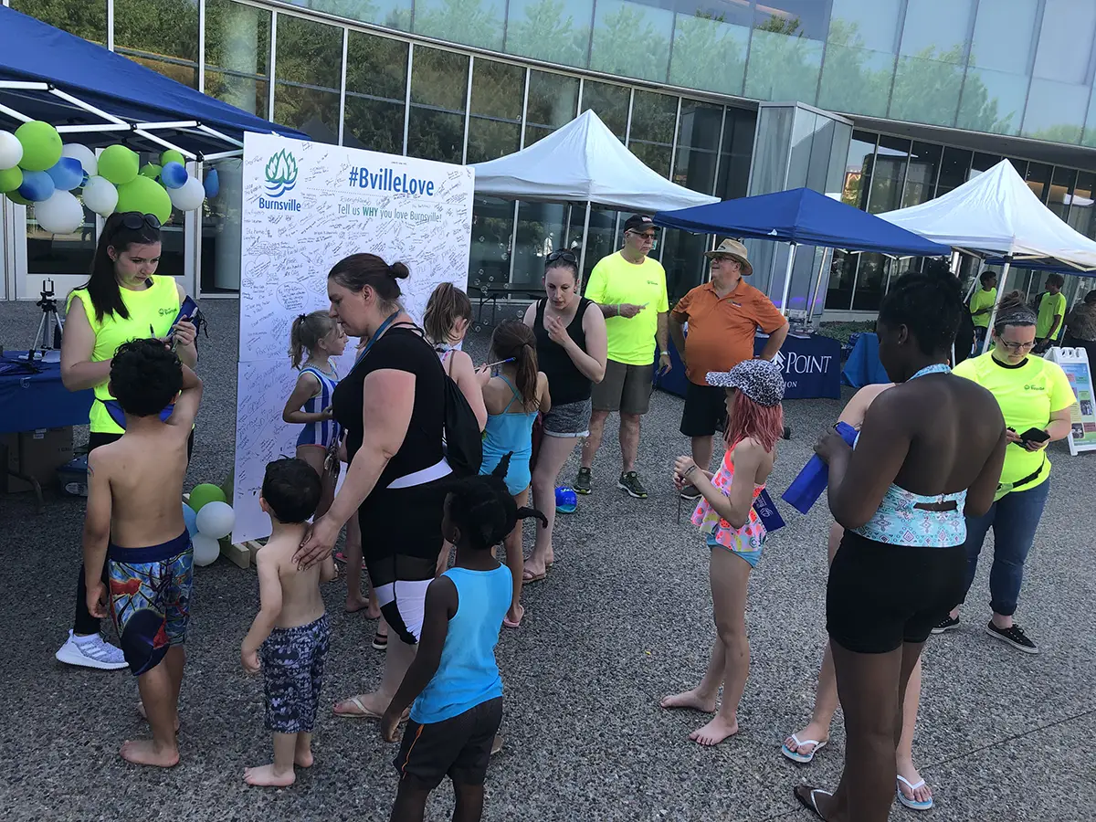 people signing 5 foot by 3 foot sign "Why they love Burnsville"